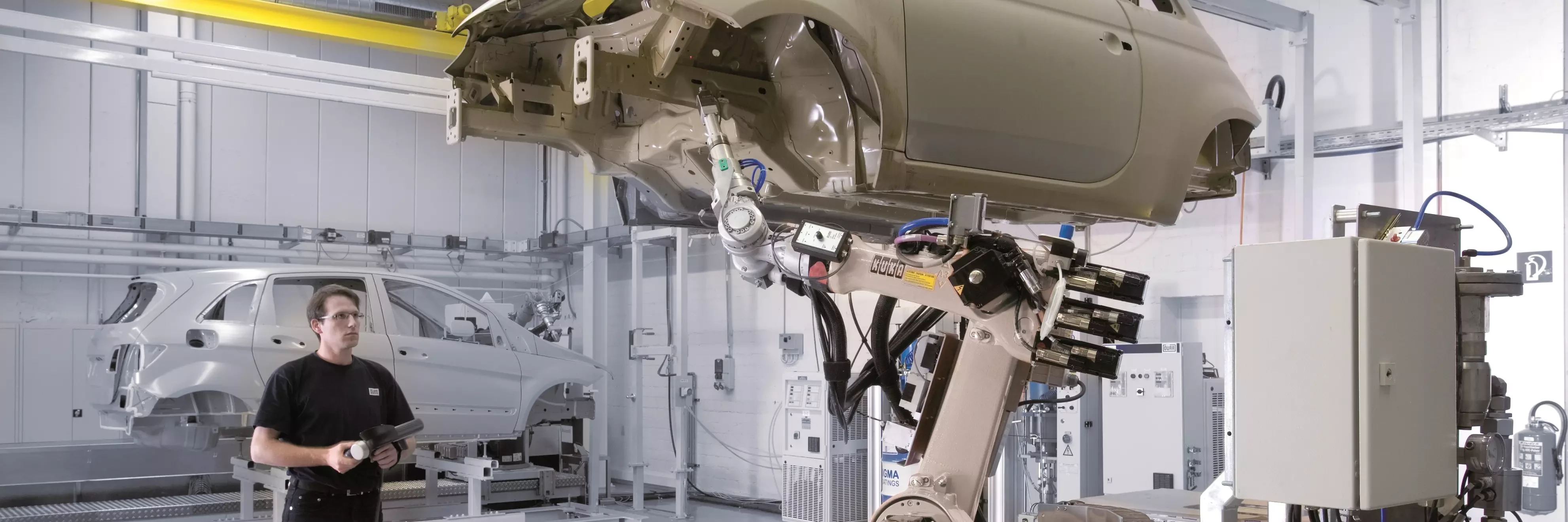 Man controls robot that lifts car body